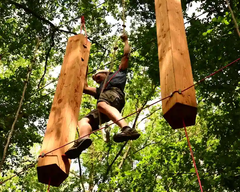Homme en équilibre sur des poutres suspendues en bois à AirParc Périgord.