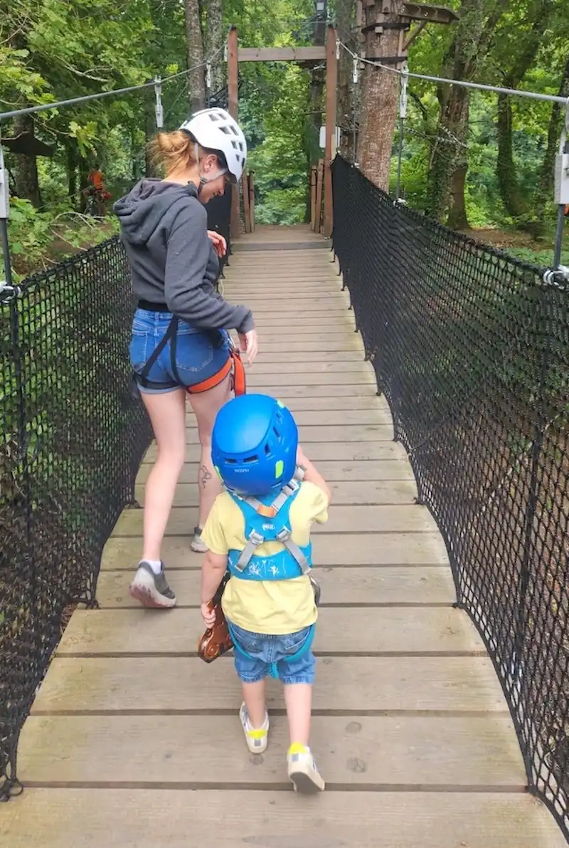 Enfant de 2 ans sur le parcours accrobranche Bambino sans baudrier à AirParc Périgord, accompagné d'un parent.