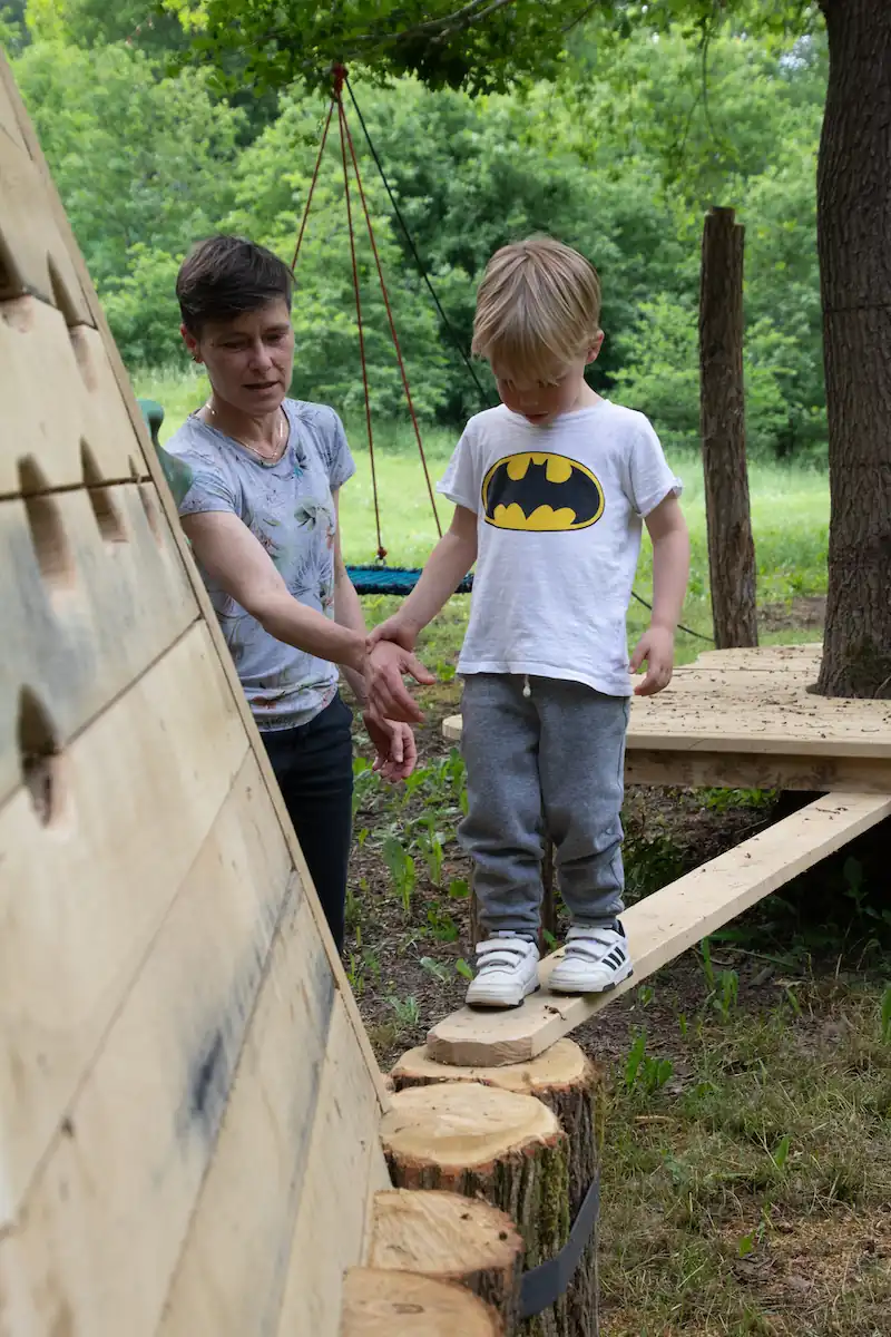 Enfant de 2 ans sur le parcours accrobranche Bambino sans baudrier à AirParc Périgord, accompagné d'un parent.